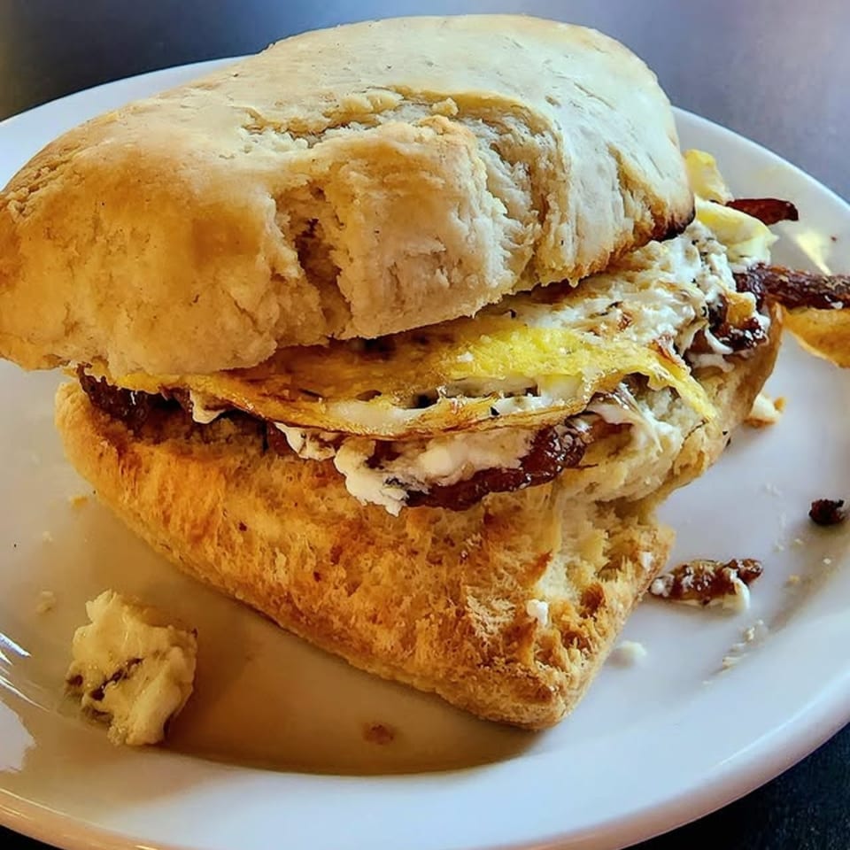 A Jim & Patty's Coffee breakfast sandwich with egg, bacon, and cheese on a biscuit.