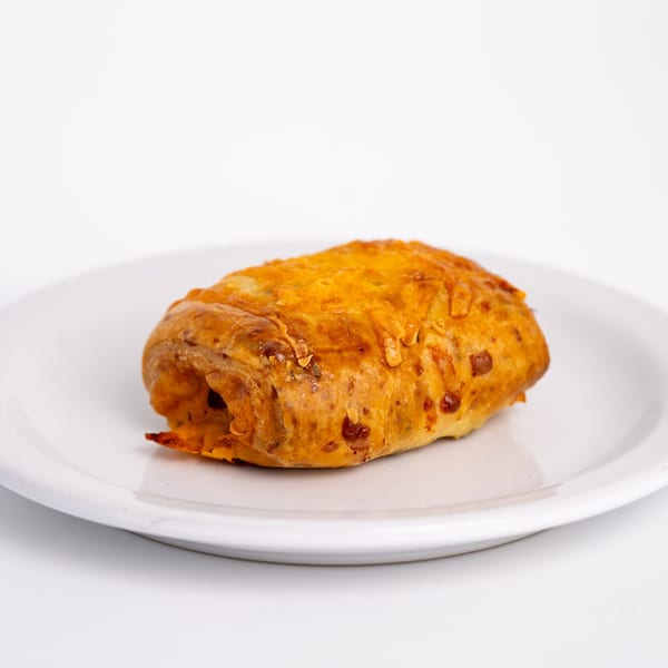 A golden-brown pastry, possibly a cheese danish, sits on a white plate.